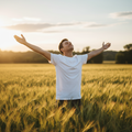 Faith-inspired lifestyle image - person in sunlit field with arms outstretched